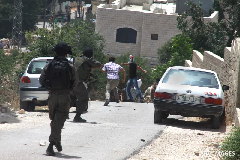 An Israeli soldier fires towards Palestinian protesters during clashes following a protest against the expropriation of Palestinian land by Israel on March 31, 2013 in the village of Kfar Qaddum, near the occupied West B...