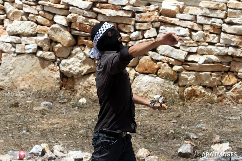 A Palestinian protester throws stones towards Israeli soldiers during clashes following a protest against the expropriation of Palestinian land by Israel on March 31, 2013 in the village of Kfar Qaddum, near the occupied...