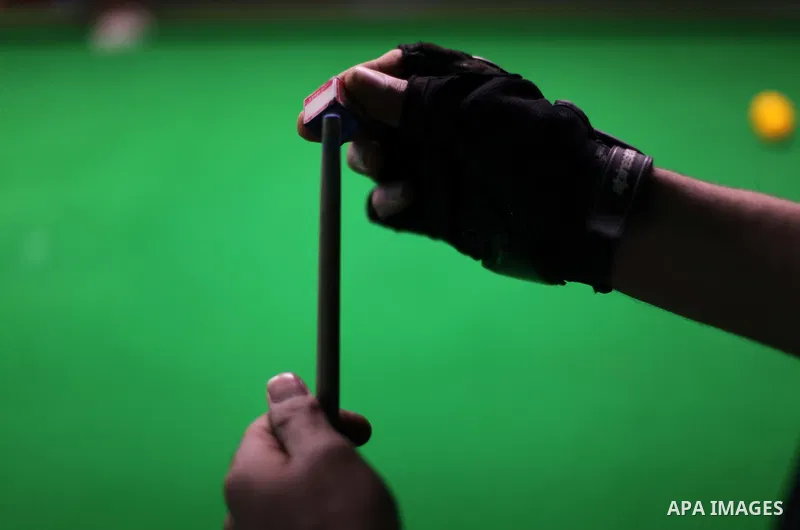 A Palestinian man strokes a cue stick at a billiard club in Gaza city June 05, 2013. Photo by Ashraf Amra