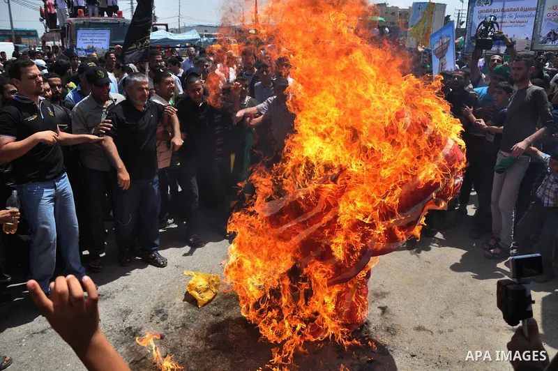 Palestinians burn a U.S flag during a protest near the border between Israel and the northern Gaza Strip June 7, 2013. The protest was part of the Global March to Jerusalem initiative, marking the 46th anniversary of Isr...