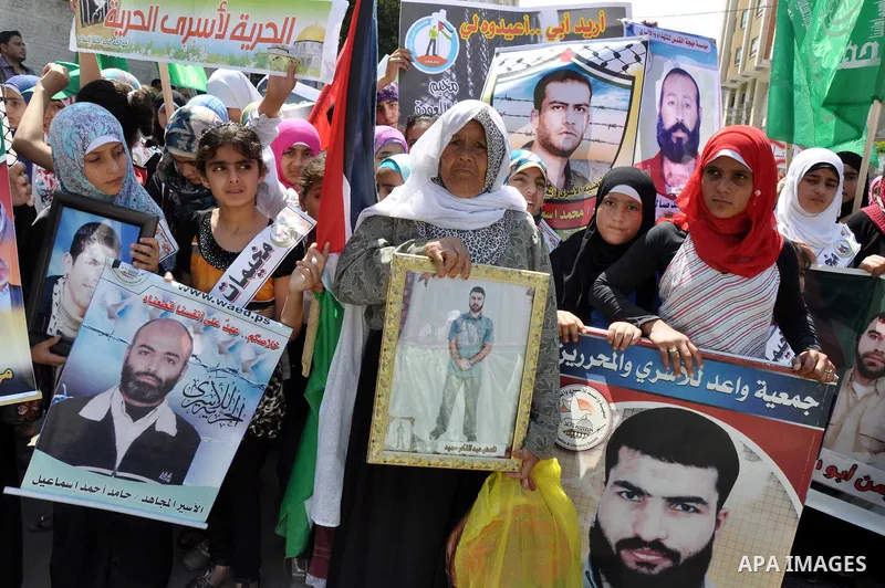 Palestinians hold pictures of prisoners held in Israeli jails during a protest outside Red Cross office in Gaza City, on June 10, 2013 in solidarity with Palestinian prisoners held by Israel to demand their release from...