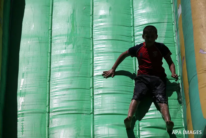 A Palestinian boy plays with water at a summer camp organised by UNRWA for students of UNRWA schools in Gaza City on June 20, 2013. Photo by Ashraf Amra