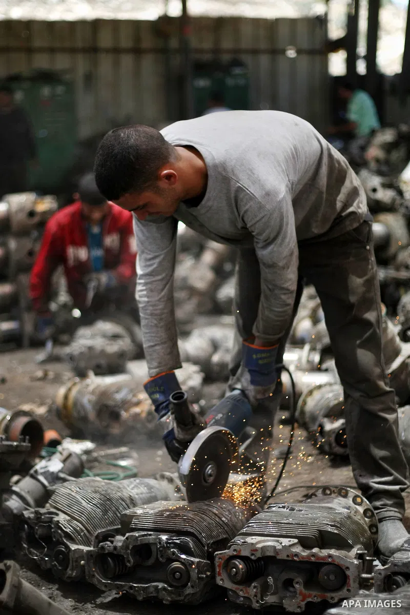 Palestinian workers cut metal scraps at a processing facility in the West Bank village of Idna near Hebron June 20, 2013. The metal is collected and later transferred to Israel where it will be melted and recycled. Photo...
