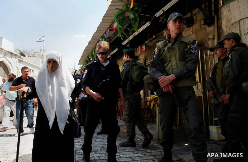 A Palestinian elderly woman walks past Israeli security guards following Friday prayers at al-Aqsa mosque, in Jerusalem's old city on June 21, 2013. A security guard shot and killed a Jewish Israeli man on Friday at one...