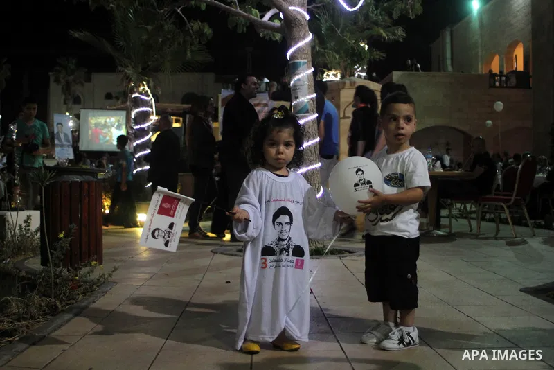 A Palestinian girl wears a T-shirt with Mohammed Assaf's picture, 23, a Palestinian finalist on the Arab Idol talent show, as others watch his televised performance in Gaza City, Friday, June 21, 2013. Assaf, Gazan's pow...