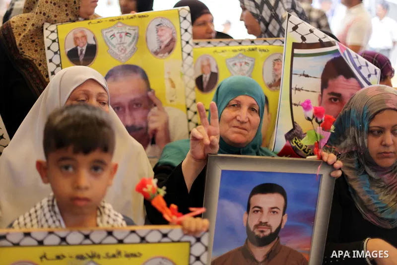 Palestinians hold pictures of prisoners held in Israeli jails during a protest outside Red Cross office in Gaza City, on June 24, 2013 in solidarity with Palestinian prisoners held by Israel to demand their release. Phot...