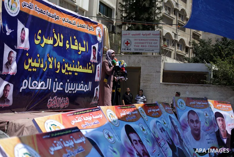 Palestinians hold banners during a protest in front of the Red Cross in Gaza city on June 26, 2013 in solidarity with Palestinian and Jordanians prisoners held by Israel to demand their release from detention without tri...