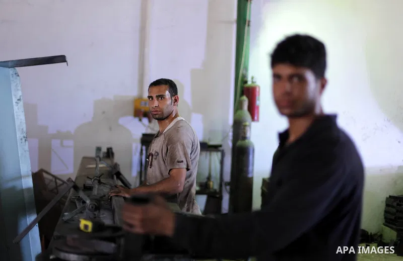 Palestinian laborers work at a production line of tipper tri-motorcycles in Khan Younis in the southern Gaza Strip June 27, 2013. The Production Line is the first of its kind in Gaza Strip which imports raw materials fro...