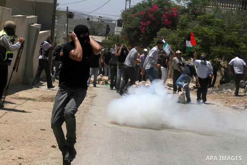 Palestinian protesters run seek for cover from tear gas fired by Israeli security forces during clashes following a protest against the expropriation of Palestinian land by Israel in the village of Kfar Qaddum near the o...
