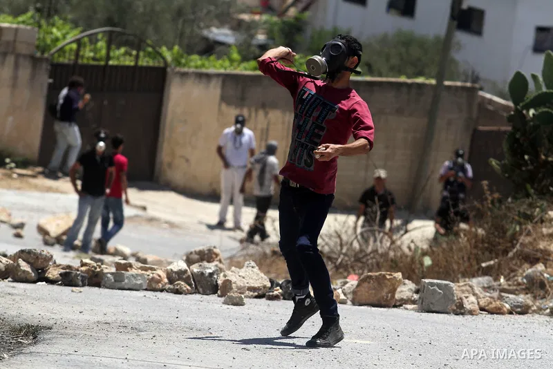 A Palestinian protester throws stones towards Israeli security forces during clashes following a protest against the expropriation of Palestinian land by Israel in the village of Kfar Qaddum near the occupied West Bank c...