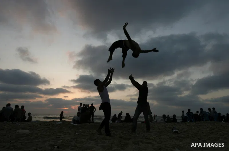 A Palestinian youth attempts a back-flip on the beach in Gaza on June 28, 2013. Gazans escape to the beach and out from their homes during heat wave and power outages. Photo by Emad Nassar
