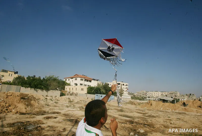 Palestinian children hold kites bearing the Turkish, Egyptian and Syria's former independence flag, which has been adopted by the rebels forces fighting agianst Syrian pro-government forces in Syria, to show their solida...