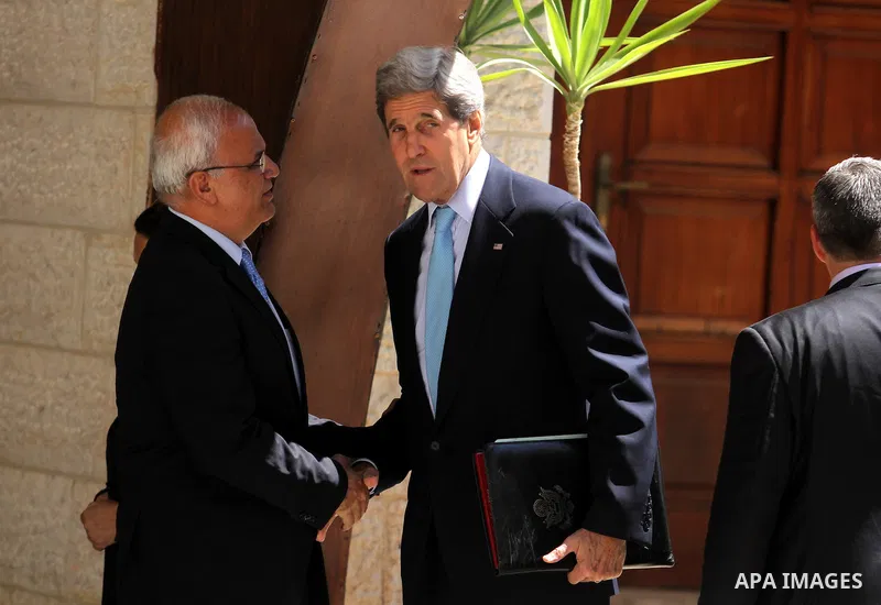U.S. Secretary of State John Kerry, right, and chief Palestinian negotiator Saeb Erekat wave upon his arrival for a meeting with Palestinian President Mahmoud Abbas in the West Bank city of Ramallah Sunday, June 30, 2013...