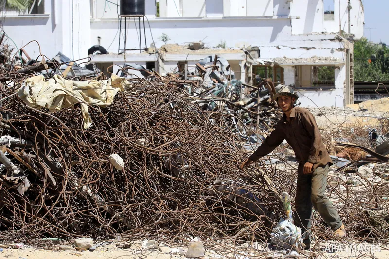 A Palestinian laborer collects used steel bars, at a site of an old prison known as al-Saraya that was destroyed by the Isreali airstrikes during the conflict between Israel and Gaza militants, in Gaza city July 4, 2013....