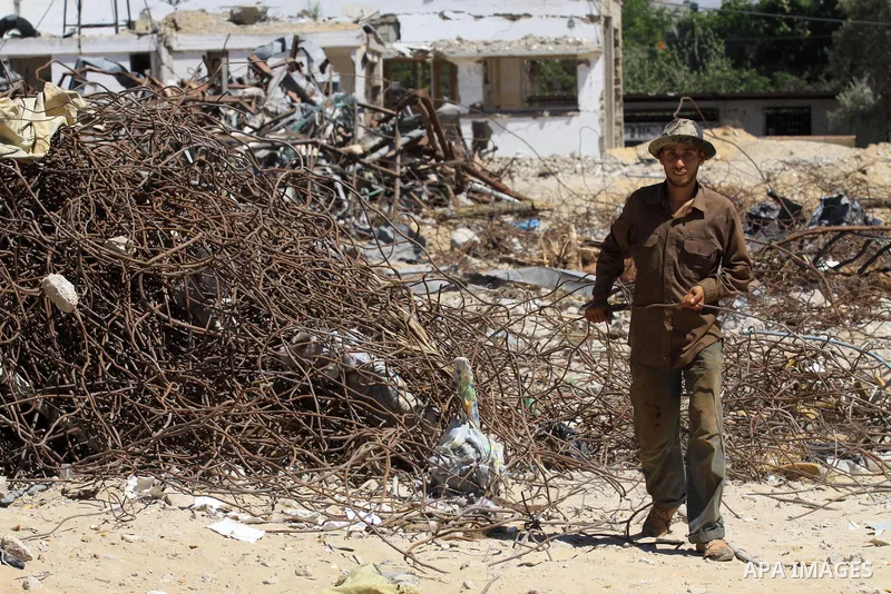 A Palestinian laborer collects used steel bars, at a site of an old prison known as al-Saraya that was destroyed by the Isreali airstrikes during the conflict between Israel and Gaza militants, in Gaza city July 4, 2013....
