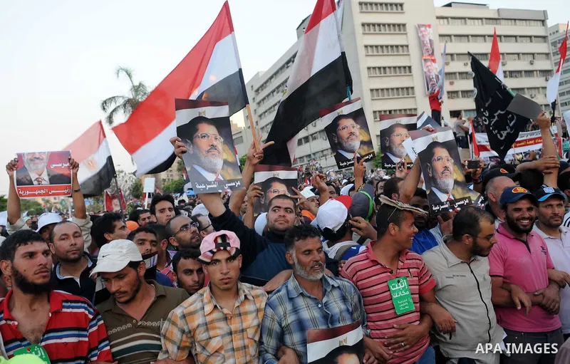Ousted President Mohamed Morsi supporters and Muslim brotherhood members shout political and hold placards in his support as they demonstrate against his toppling at Raba al-Adawyia mosque on July 7, 2013 in Cairo. Carry...