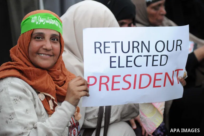 Ousted President Mohamed Morsi supporters and Muslim brotherhood members shout political and hold placards in his support as they demonstrate against his toppling at Raba al-Adawyia mosque on July 7, 2013 in Cairo. Carry...