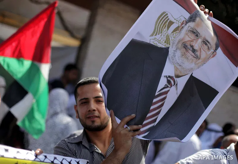 Families of Palestinian prisoners hold pictures of Egyptian President Mohamed Mursi during a protest to show support to him outside Red Cross office in Gaza City, on July 08, 2013. Photo by Ashraf Amra