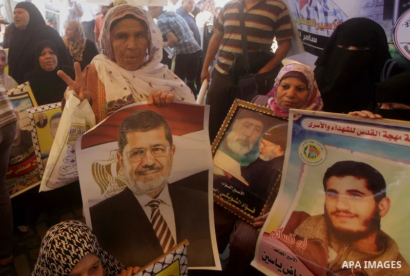 Families of Palestinian prisoners hold pictures of Egyptian President Mohamed Mursi during a protest to show support to him outside Red Cross office in Gaza City, on July 08, 2013. Photo by Ashraf Amra