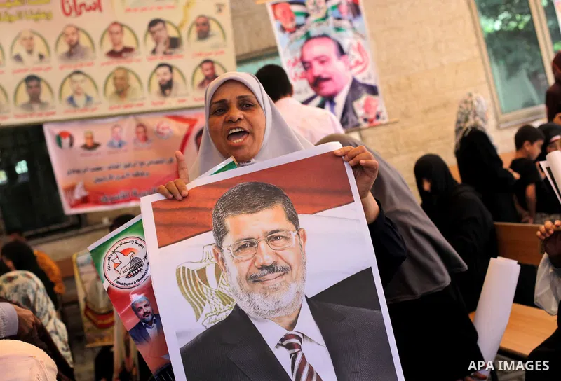 Families of Palestinian prisoners hold pictures of Egyptian President Mohamed Mursi during a protest to show support to him outside Red Cross office in Gaza City, on July 08, 2013. Photo by Ashraf Amra