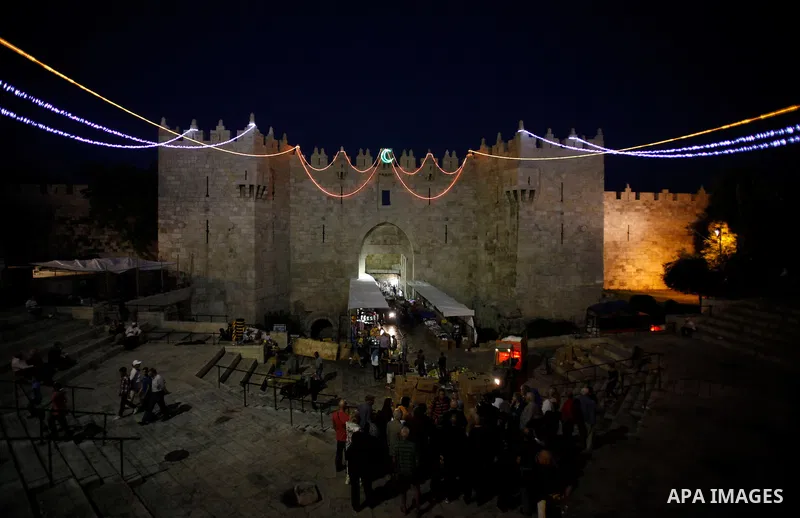 Palestinians walk at Damascus gate decorated by lights in Jerusalem's old city, on July 8, 2013, as people prepare for the upcoming Muslim holy fasting month of Ramadan. Muslims around the world celebrate Ramadan, the ho...