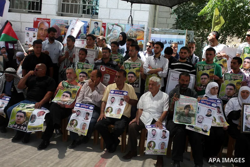 Palestinians hold pictures of prisoners held in Israeli jails during a protest outside Red Cross office in the West Bank City of Ramallah, on July 9, 2013 in solidarity with Palestinian prisoners held by Israel to demand...