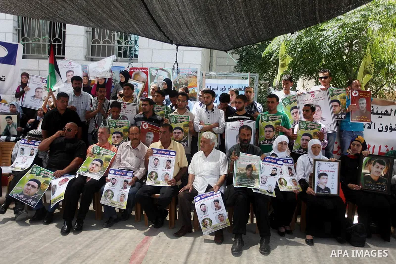 Palestinians hold pictures of prisoners held in Israeli jails during a protest outside Red Cross office in the West Bank City of Ramallah, on July 9, 2013 in solidarity with Palestinian prisoners held by Israel to demand...
