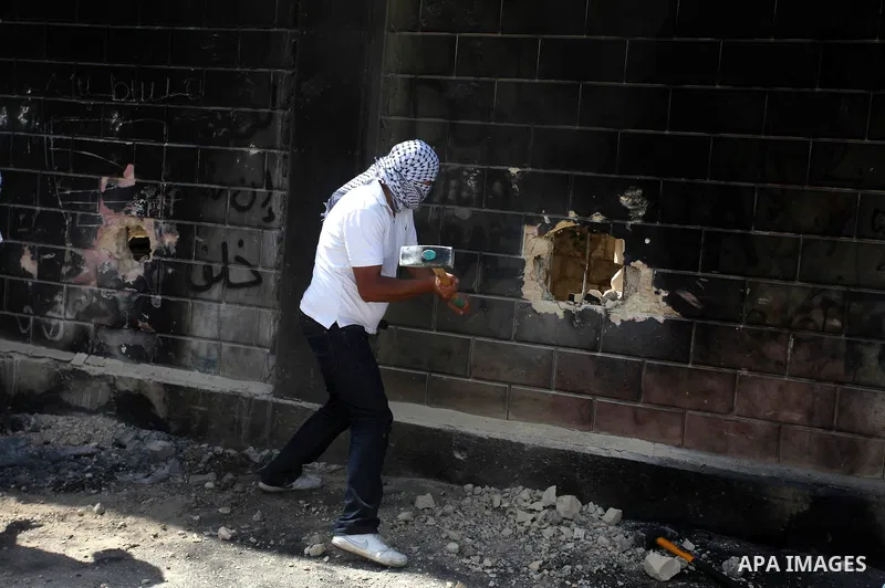 A Palestinian youth uses sledge hammer to knock holes through part of a wall connected to Israel's controversial separation barrier in the Abu Dis neighborhood, bordering Jerusalem on July 9, 2013. Israel says the barrie...
