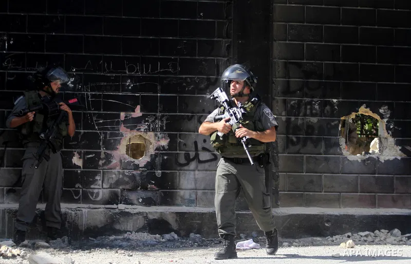 Israeli security, guard the holes knocked through part of Israel's controversial separation barrier by Palestinian youth, in the Abu Dis neighborhood, bordering Jerusalem, on July 9, 2013. Israel says the barrier is need...