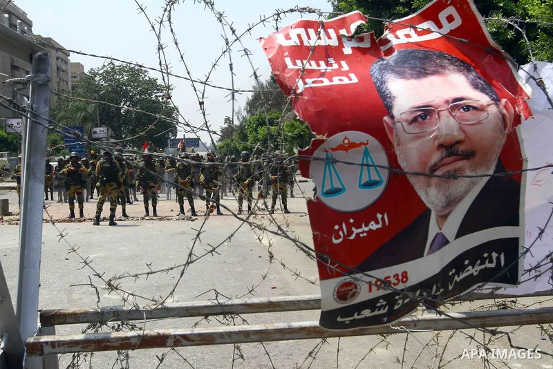 A poster of deposed president Mohamed Morsi hangs on barbed wire that blocks the access to the headquarters of the Republican Guard in Cairo on July 9, 2013. Egypt's armed forces warned in a statement against any attempt...