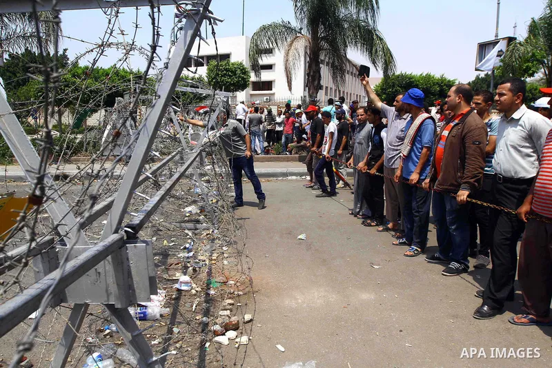 Supporter of ousted president Mohamed Morsi stand in front of a barbed wire that blocks the access to the headquarters of the Republican Guard in Cairo on July 9, 2013. Egypt's armed forces warned in a statement against...