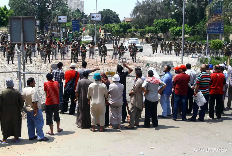 Supporter of ousted president Mohamed Morsi stand in front of a barbed wire that blocks the access to the headquarters of the Republican Guard in Cairo on July 9, 2013. Egypt's armed forces warned in a statement against...
