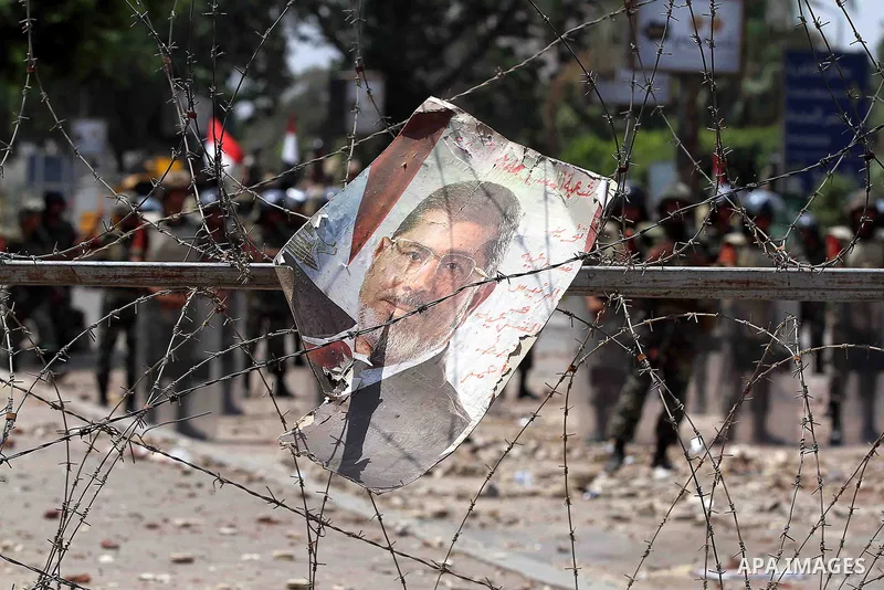 A poster of deposed president Mohamed Morsi hangs on barbed wire that blocks the access to the headquarters of the Republican Guard in Cairo on July 9, 2013. Egypt's armed forces warned in a statement against any attempt...