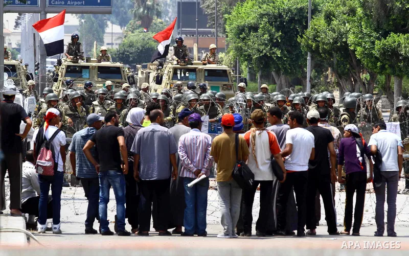 Supporter of ousted president Mohamed Morsi stand in front of a barbed wire that blocks the access to the headquarters of the Republican Guard in Cairo on July 9, 2013. Egypt's armed forces warned in a statement against...