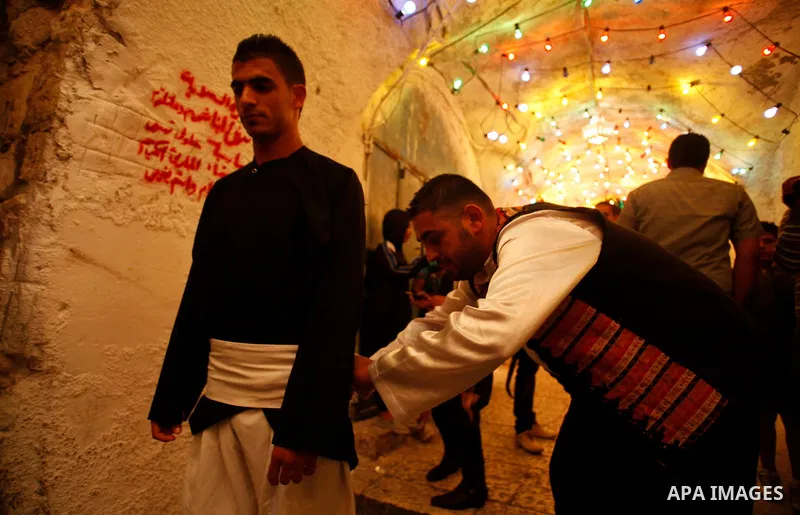 A Palestinian dawn awakener, al-Musaharati in Arabic, adjusts his colleague uniform before walk through streets to wake up Muslims for a meal before sunrise during the fasting month of Ramadan, in Jerusalem's old city on...