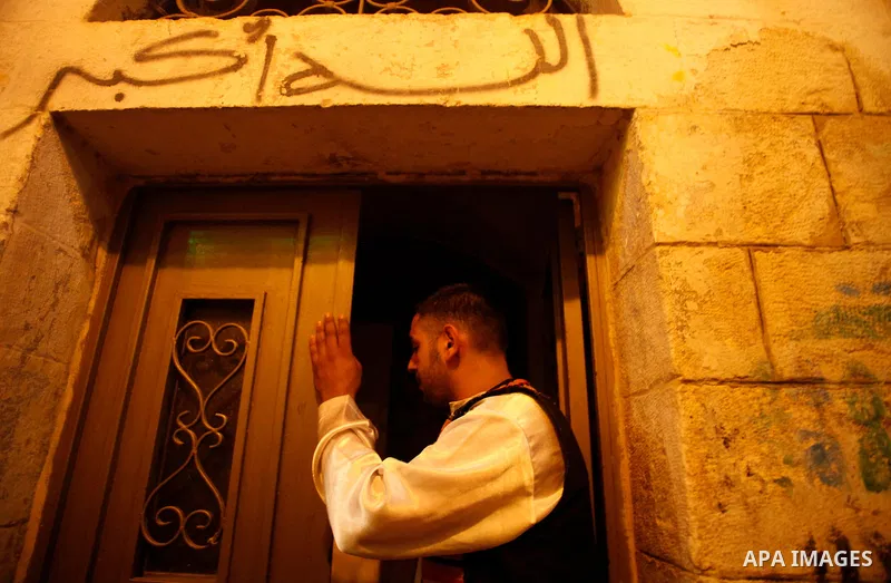 A Palestinian dawn awakener, knocks a door as he walks through streets to wake up Muslims for a meal before sunrise during the fasting month of Ramadan, in Jerusalem's old city on July 13, 2013. Al-Musaharati is an old p...