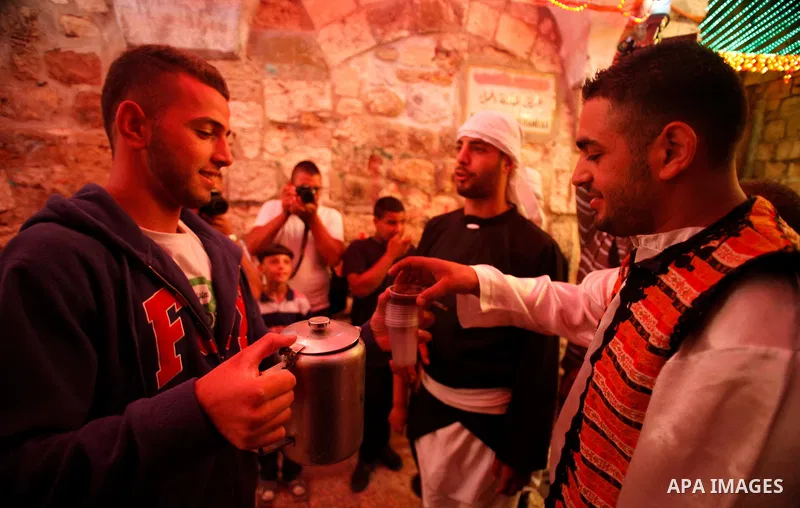 A Palestinian man allocates juice for dawn awakeners, al-Musaharati in Arabic, as they walk through streets to wake up Muslims for a meal before sunrise during the fasting month of Ramadan, in Jerusalem's old city on Jul...