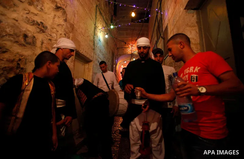 A Palestinian man allocates juice for dawn awakeners, al-Musaharati in Arabic, as they walk through streets to wake up Muslims for a meal before sunrise during the fasting month of Ramadan, in Jerusalem's old city on Jul...