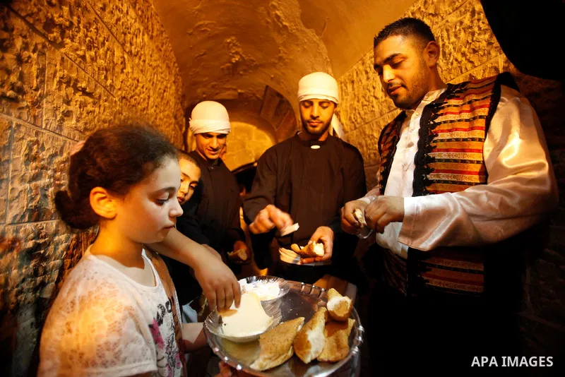 A Palestinian girl serves bread and cheese for dawn awakeners, al-Musaharati in Arabic, as they walk through streets to wake up Muslims for a meal before sunrise during the fasting month of Ramadan, in Jerusalem's old ci...