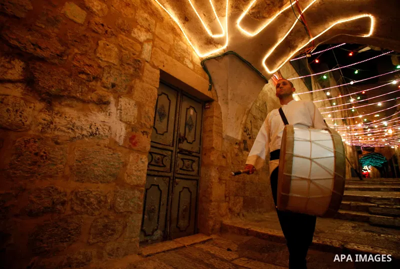 A Palestinian dawn awakener, al-Musaharati in Arabic, beats his drum to wake up Muslims for a meal before sunrise as he walks through streets during the fasting month of Ramadan, in Jerusalem's old city on July 13, 2013....