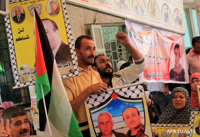 Palestinians hold pictures of prisoners held in Israeli jails during a protest outside Red Cross office in Gaza City, on July 15, 2013 in solidarity with Palestinian prisoners held by Israel to demand their release. Phot...