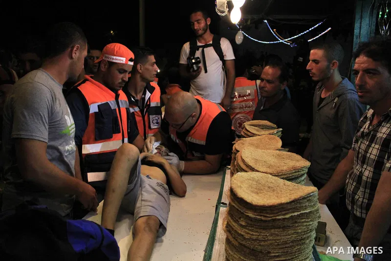 Palestinian paramedics help a wounded man during clash with Palestinian protestors outside the Damascus gate in Jerusalem on July 15, 2013 during a demonstration against the Israeli government's plans to relocate Bedouin...