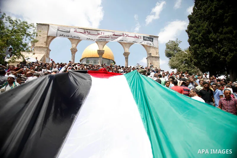 Palestinian demonstrators hold their national flag during a rally of supporters of Fatah movement in solidarity with prisoners in Israeli jails, following Friday prayers at Al-Aqsa Mosque compound in Jerusalem on July 19...