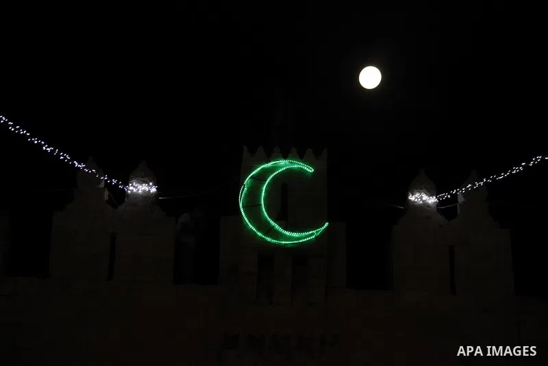 The moon is seen above a Damascus gate decorated by lights at the al-Aqsa mosque compound in the old city of Jerusalem on July 22, 2013. Photo by Saeed Qaq