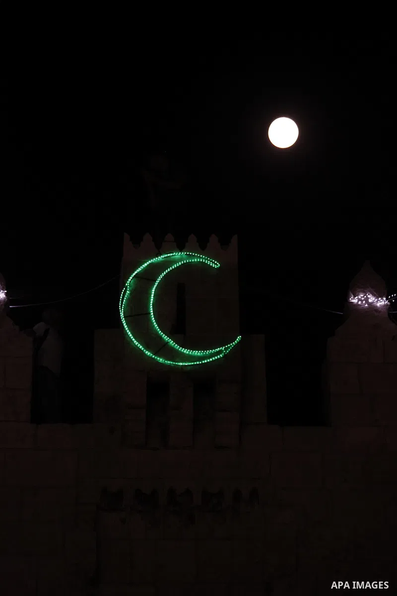The moon is seen above a Damascus gate decorated by lights at the al-Aqsa mosque compound in the old city of Jerusalem on July 22, 2013. Photo by Saeed Qaq