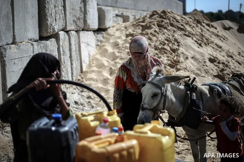 A Palestinian woman fills bottels with water from a public tap in Khan Younis in southern Gaza strip, July 28, 2013. Photo by Mahmoud Hamda