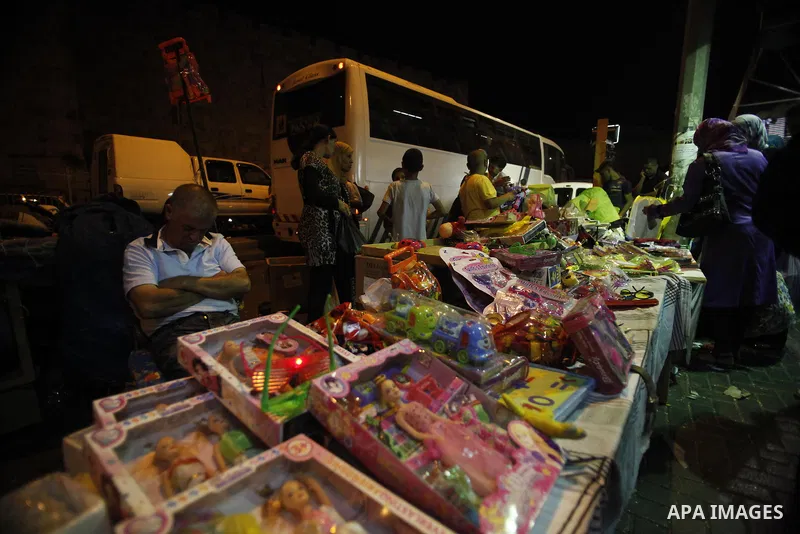 Palestinians buy games at a street market during preparations for the upcoming Eid al-Fitr festival which is celebrated at the end of holy fasting month of Ramadan, in Jerusalem city Aug 06, 2013, as Muslims over the wor...