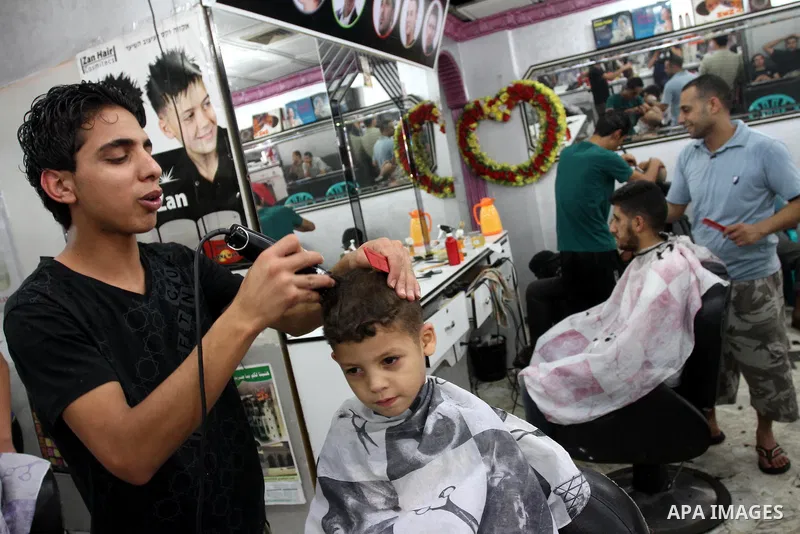 Palestinian barbers cut hair for youths at a shop during preparations for the Eid Al-Fitr feast in Gaza city on Aug 07, 2013, as Muslims over the world prepare to celebrate Eid al-Fitr, a three day holiday marking the en...