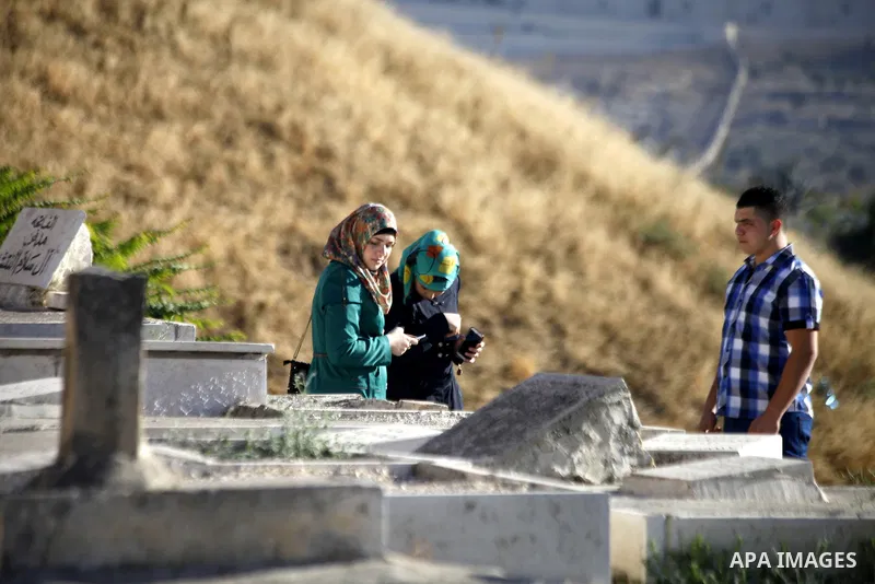 Palestinians visit the graves of a relatives as part of tradition during the first day of Eid al-Fitr which marks the end of the Muslim fasting month of Ramadan, outside Jerusalem's Old City, on Aug. 08, 2013. Muslims ar...