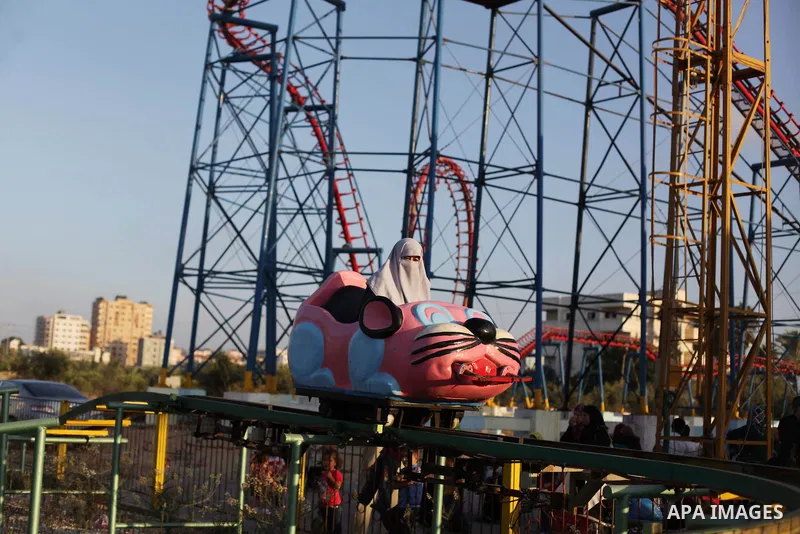 Palestinians enjoy a ride in an amusement park on the third day of Eid al-Fitr, marking the end of Islam's fasting holy month of Ramadan, in Gaza City on August 10, 2013. Photo by Ashraf Amra